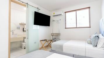 A hotel room with a bed, a TV, a shower, and a window.