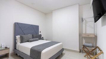Un dormitorio moderno con cama, mesita de noche y televisor montado en la pared.