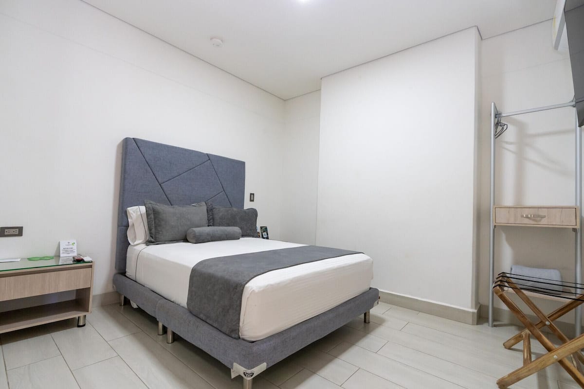 A modern bedroom with a bed, bedside table, and a wooden shelf unit.