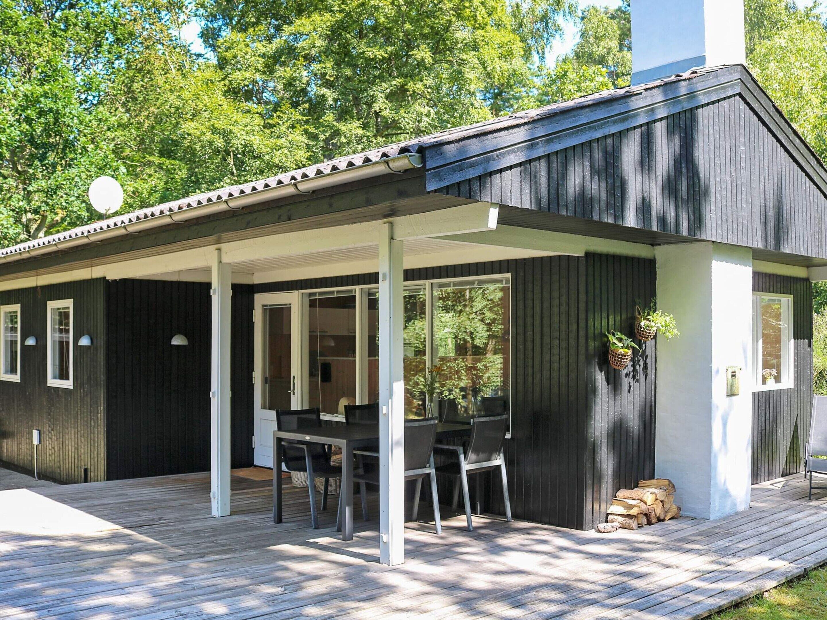 A modern house with a covered patio, large windows, and a wooden deck.