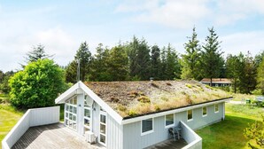 A house with a sloped roof, a wooden deck, and a large windowed porch. - 8 Person Holiday Home in Blokhus (Blokhus)