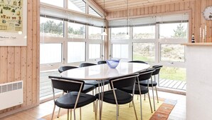 A modern dining area with a round table, black chairs, and a blue bowl. - 8 Person Holiday Home in Blokhus (Blokhus)