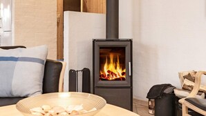 A cozy living room with a modern fireplace, a comfortable sofa, and a bowl of snacks on a round table. - 8 Person Holiday Home in Blokhus (Blokhus)