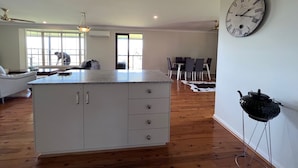 A spacious kitchen with a central island, a dining area with a table and chairs, and a large wall clock. - Scenic View Esk Escape (Esk)