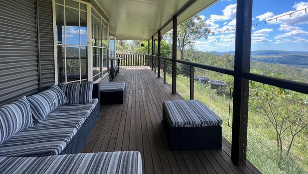A covered porch with a wooden floor, a sofa, and a bench. - Scenic View Esk Escape (Esk)