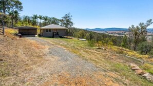 A house with a garage and a covered porch, surrounded by dry grass and sparse trees. - Scenic View Esk Escape (Esk)