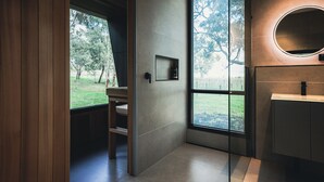 A modern bathroom with a large window, a wooden chair, and a round mirror. - CABN McLaren Vale (McLaren Flat)