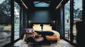 A modern bedroom with a large bed, leather chairs, and a view of the outdoors. - CABN McLaren Vale (McLaren Flat)