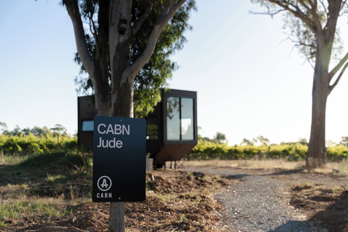A sign for 'CABN Jude' with a modern building in the background.