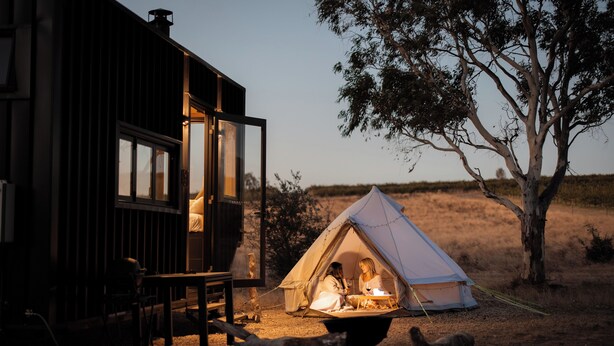 A rustic cabin with a dining area and a tent set up nearby. - CABN McLaren Vale (McLaren Flat)