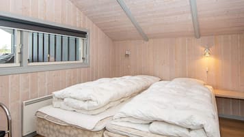 Una habitación con dos camas, una ventana con vistas y un aplique de pared.