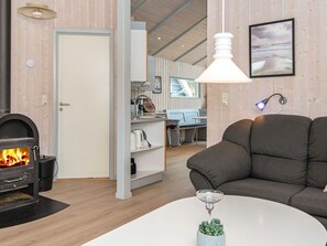 A cozy living room with a fireplace, a sofa, a coffee table, and a dining area with a view.