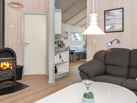 A cozy living room with a fireplace, a sofa, a coffee table, and a dining area with a view.