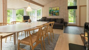 A modern interior with a wooden ceiling, a dining area with a white table and wooden chairs, a grey sofa, and a painting on the wall. - 8 Person Holiday Home in Albaek (Aalbaek)