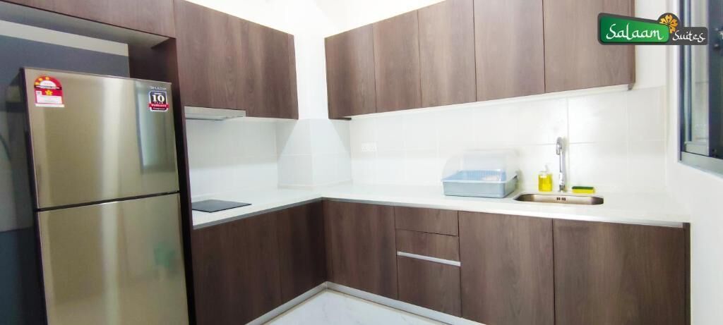 A compact kitchen with dark wooden cabinets, a stainless steel refrigerator, and a white countertop.