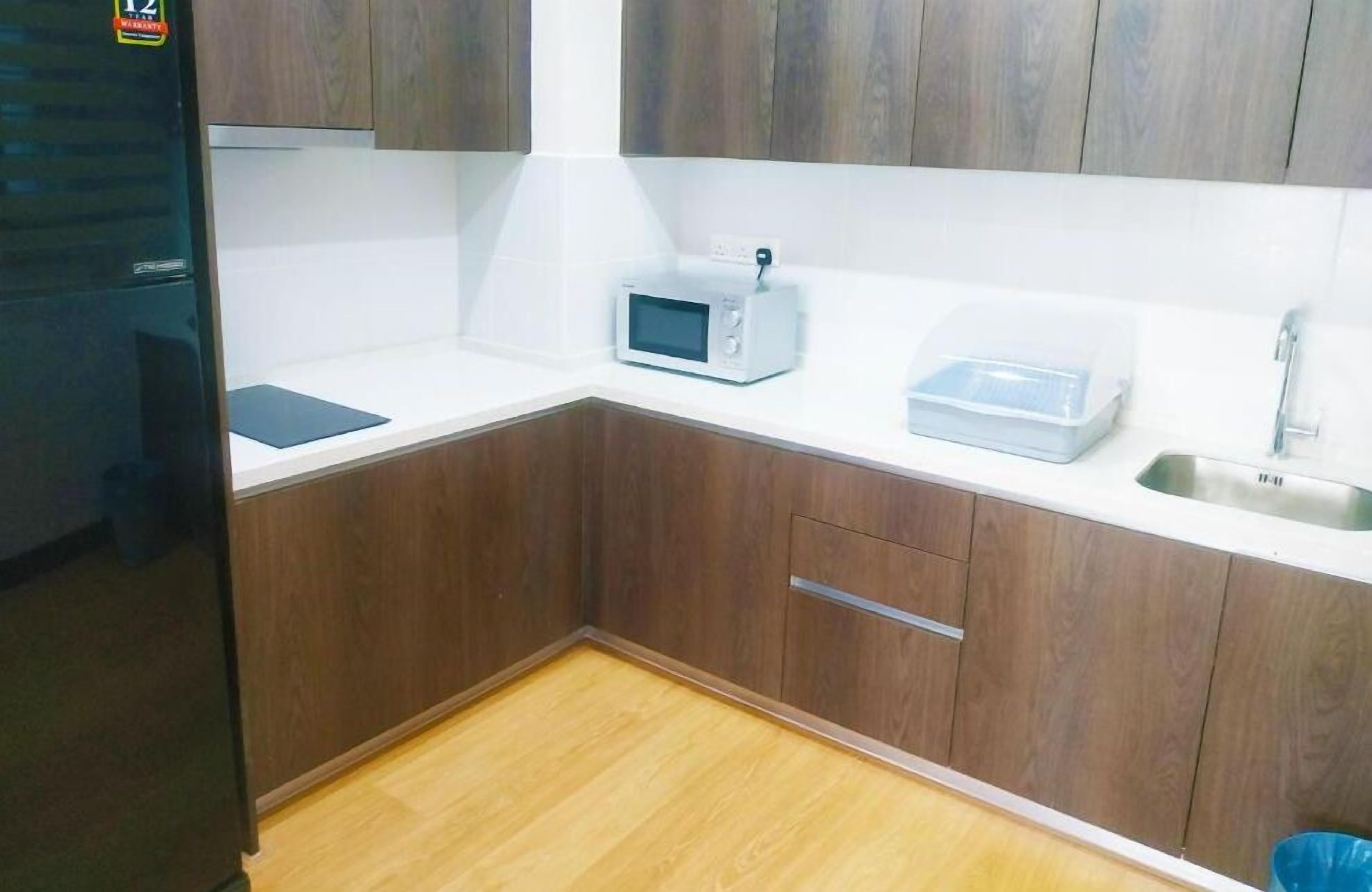 Une cuisine compacte avec des meubles en bois, un four à micro-ondes, un évier et un petit plan de travail.