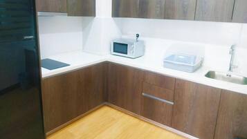 Une cuisine compacte avec des meubles en bois, un four à micro-ondes, un évier et un petit plan de travail.