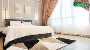 Un dormitorio moderno con una cama grande, mesitas de noche y vistas al exterior a través de cortinas translúcidas.