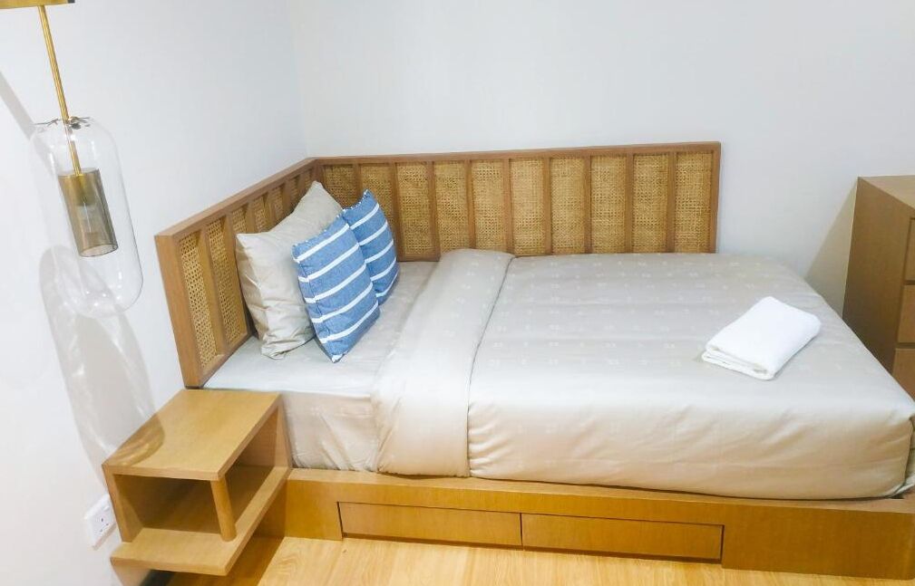 A single bed with a wooden headboard, a bedside table, and a lamp.