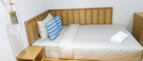 A single bed with a wooden headboard, a bedside table, and a lamp.