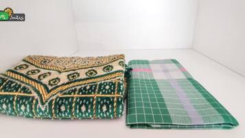 Deux couvertures pliées, l’une avec un motif vert et beige, et l’autre avec un motif à carreaux verts et blancs.