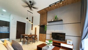 Una sala moderna con un sofá, una mesa de centro, un televisor y un comedor con sillas y una mesa.