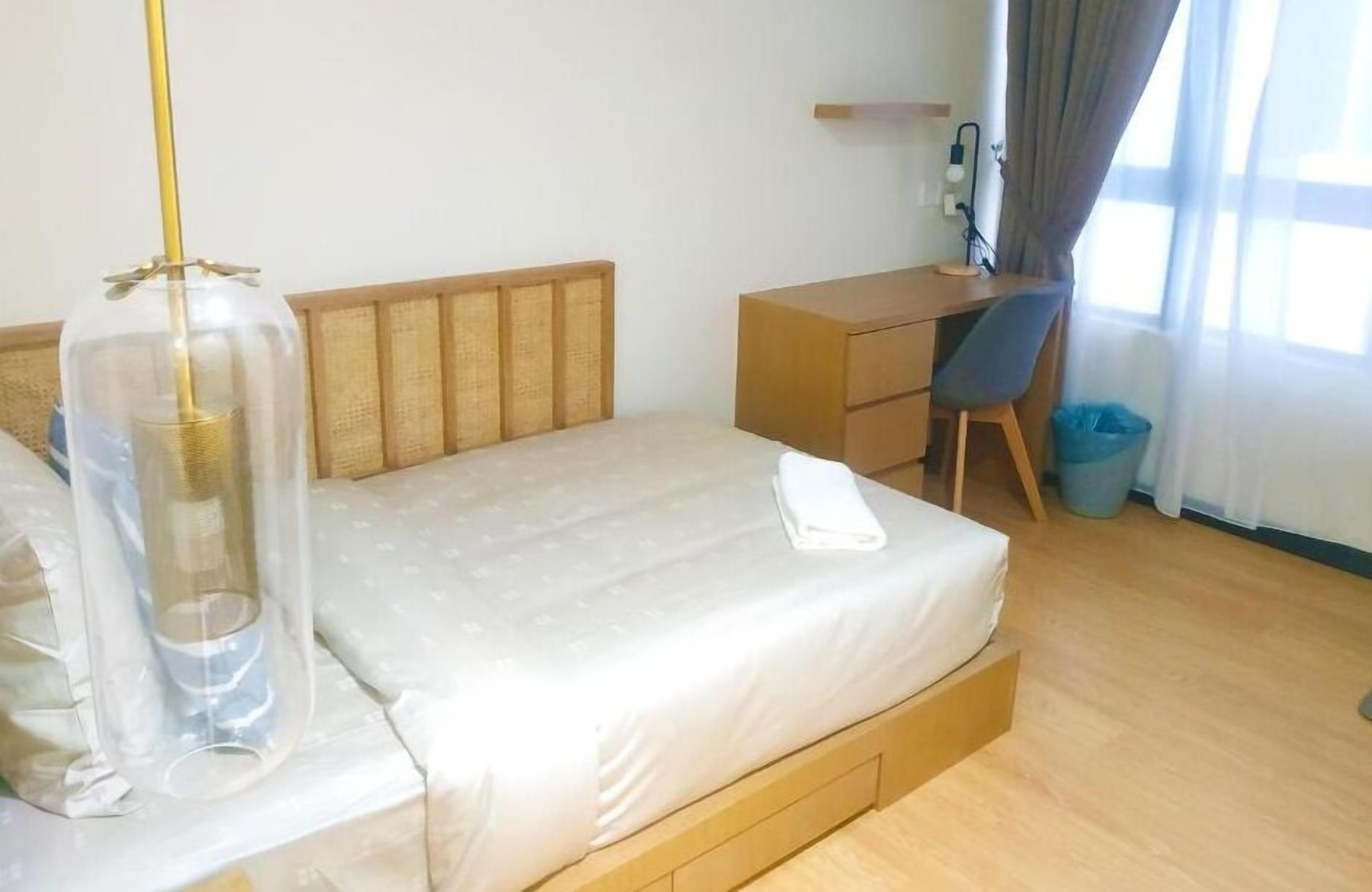 Ein Hotelzimmer mit einem Bett, einem Schreibtisch, einem Sessel und einem Fenster mit Vorhängen.
