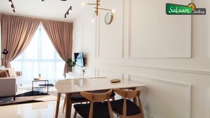 Una sala de estar moderna con un sofá, una mesa de comedor con sillas, un televisor y un amplio ventanal con cortinas.