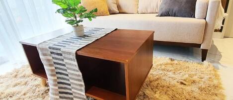 A modern living room with a sofa, a patterned coffee table, and a potted plant.