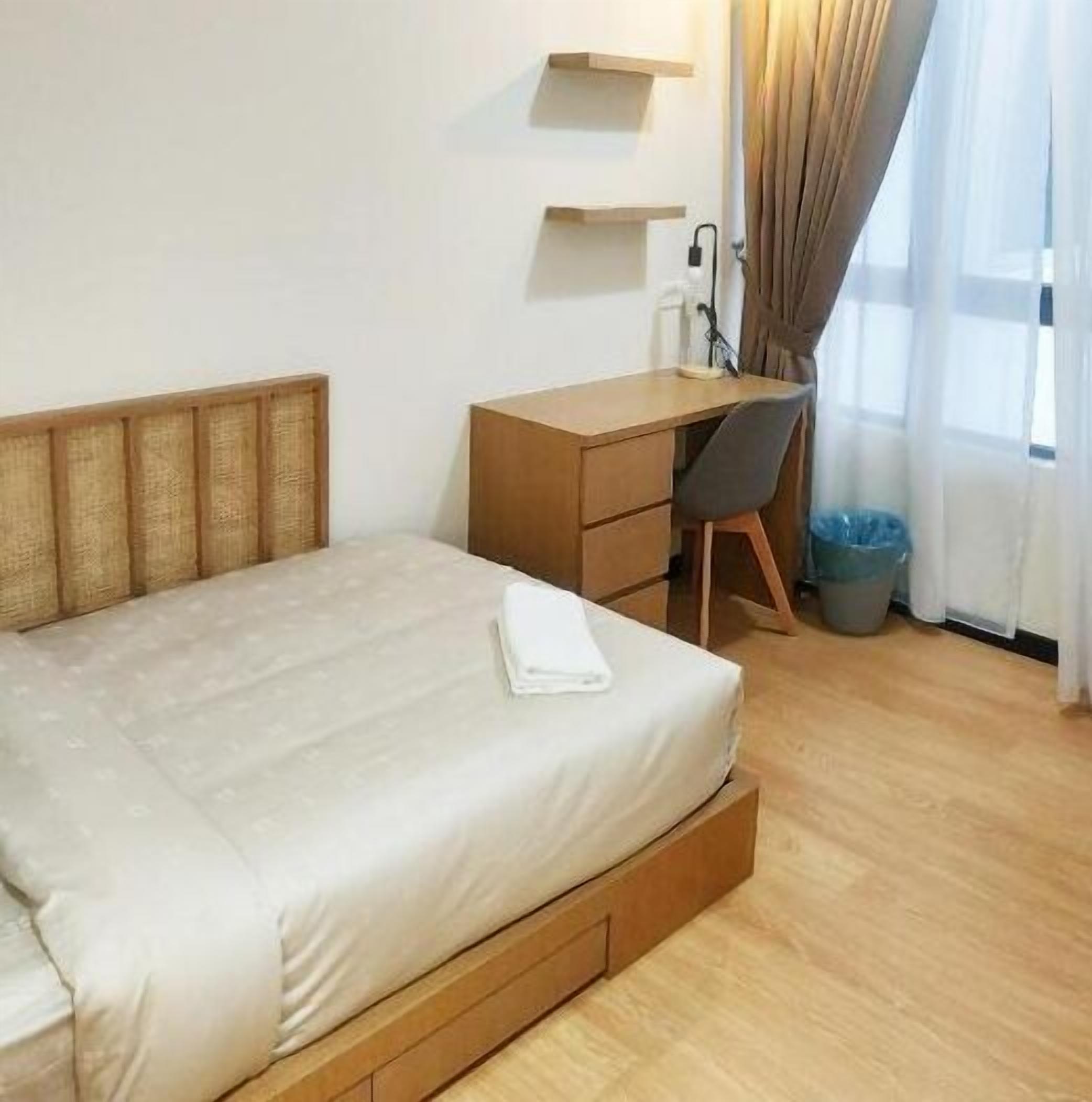 A hotel room with a bed, a desk, a chair, and a window with curtains.