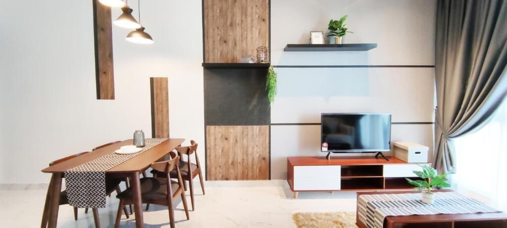Un salon moderne avec une table à manger en bois, des chaises, un téléviseur posé sur un meuble en bois et une plante sur l’étagère.