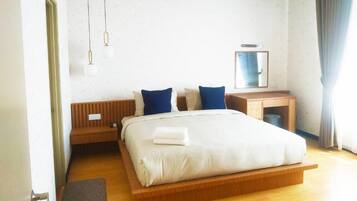 Ett modernt hotellrum med en säng i trä, ett sängbord, en spegel och ett skrivbord.