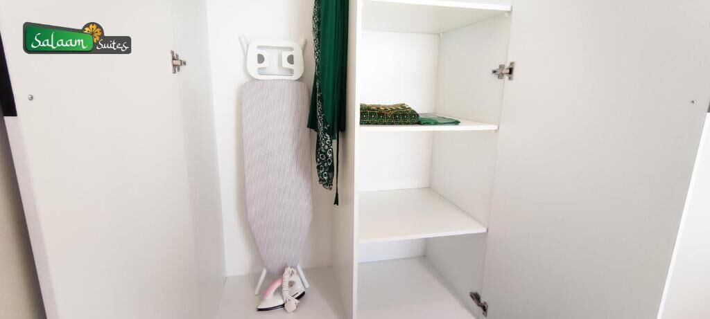 A hotel room with a white door, a hanging garment steamer, and a green towel.