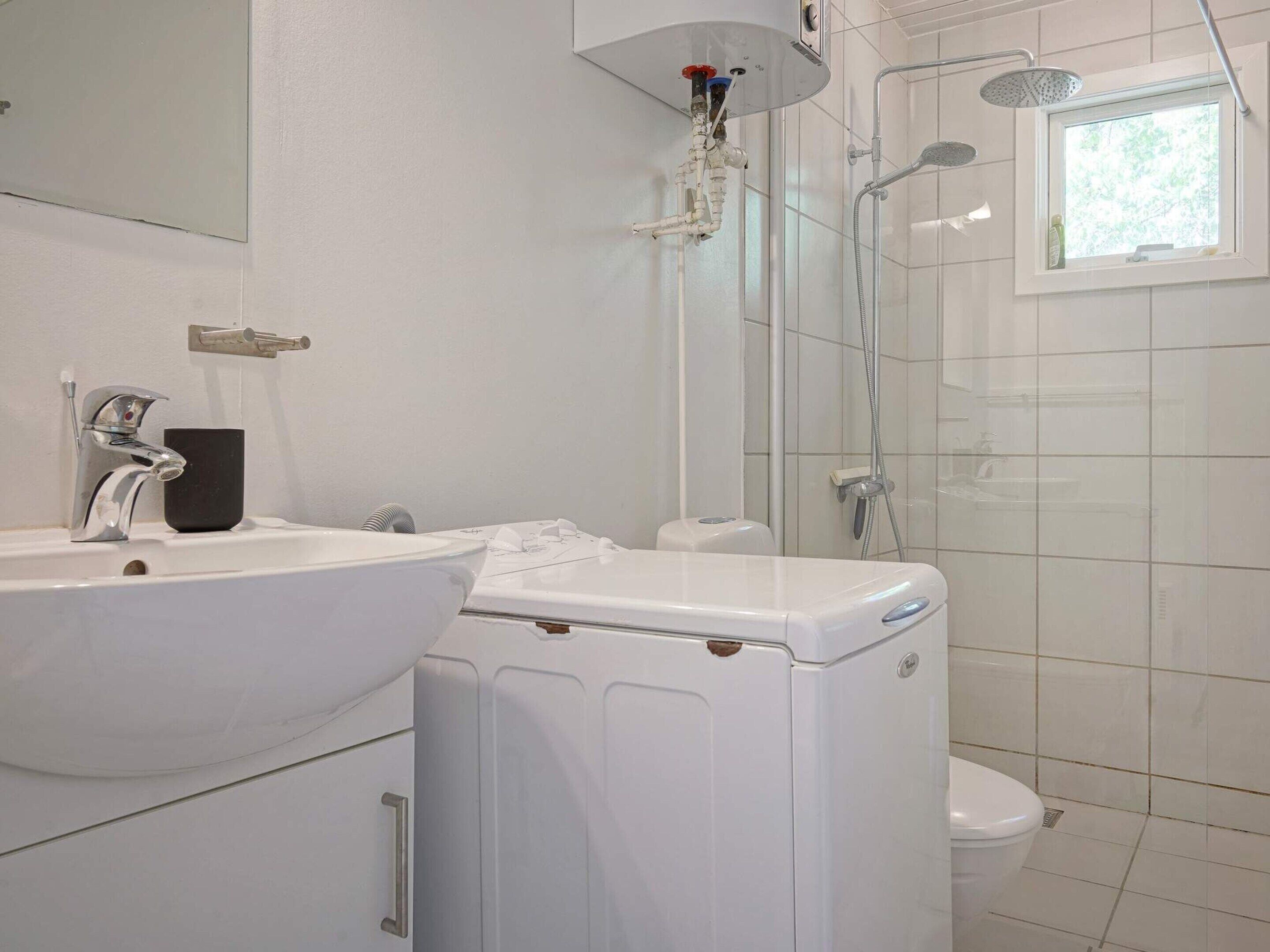 A bathroom with a white sink, a toilet, and a shower area.