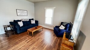 Un salon avec un canapé bleu, une table basse en bois et un meuble pour la télévision.