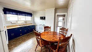 Une cuisine compacte comprenant une table et des chaises, un réfrigérateur, une cuisinière et des placards.
