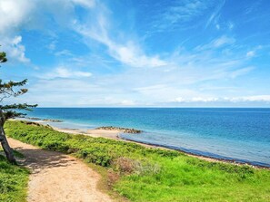 A coastal path leading to a beach with clear skies and calm waters.
