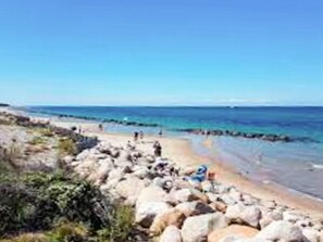 A rocky beach with clear blue water and a clear sky.