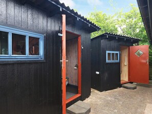 A wooden building with a red door and a blue window. - 4 Person Holiday Home in Bogense (Bogense)
