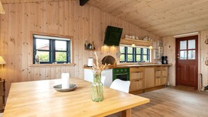 A wooden interior with a dining table, chairs, a kitchen with a stove, and a window. - 4 Person Holiday Home in Bogense (Bogense)