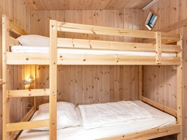 Una cama litera con estructura de madera y ropa de cama blanca.