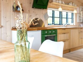 Una cocina con armarios de madera, horno verde y un florero con plantas secas en la encimera.