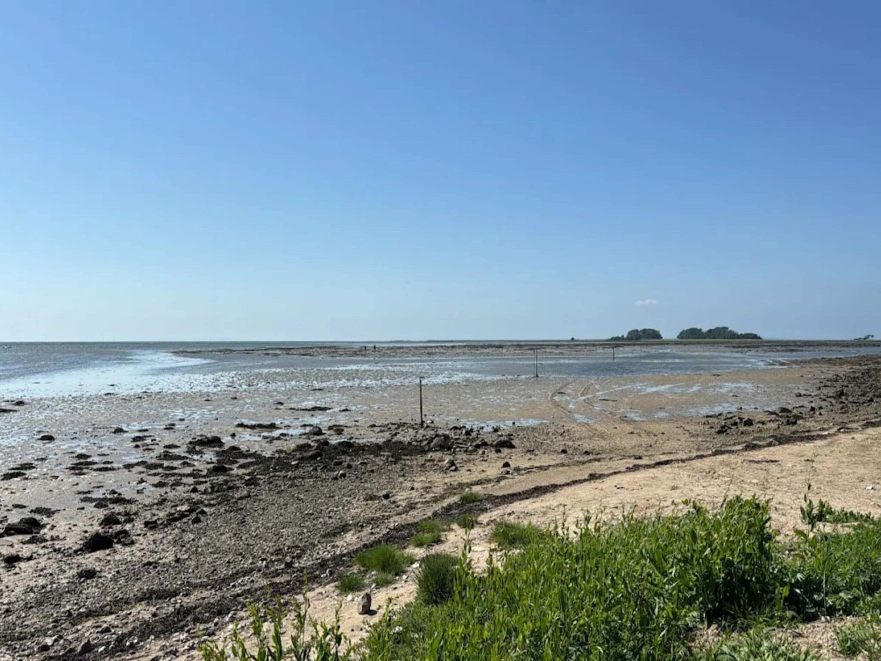 A beach with a wide sandy area and a rocky shoreline.