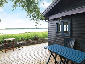 A wooden deck with a table and chairs, overlooking a lake.
