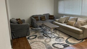 Un salon avec un canapé gris, un canapé beige et une table basse.