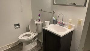 Une salle de bain avec des toilettes, un lavabo et un miroir.