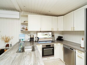 A modern kitchen with white cabinets, stainless steel appliances, and a wooden countertop. - 4 Star Holiday Home in Vejby (Vejby)