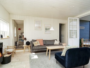 A cozy living room with a striped sofa, a dark blue armchair, a small table, and a fireplace. - 4 Star Holiday Home in Vejby (Vejby)