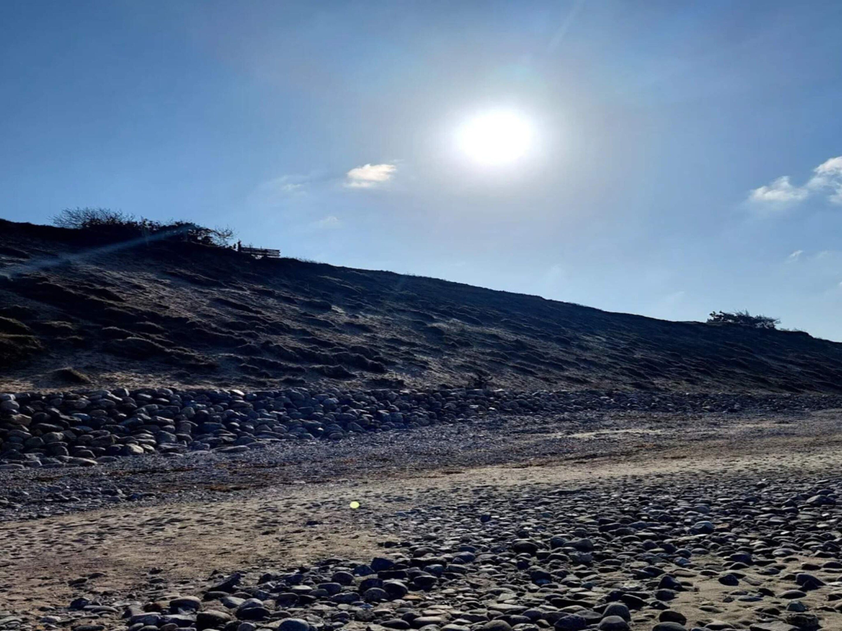 Paisagem rochosa com céu límpido e sol brilhante.