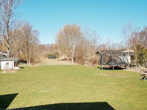 A grassy yard with a small shed, a trampoline, and leafless trees. - 4 Star Holiday Home in Vejby (Vejby)